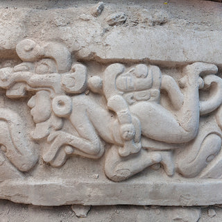 Close-up of Mayan carved stone relief showing stylized human figures in relief, in El Mirador Guatemala